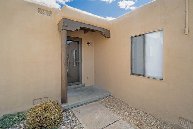 view of exterior entry featuring visible vents and stucco siding