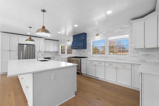 kitchen featuring custom range hood, high end appliances, light wood finished floors, and a sink