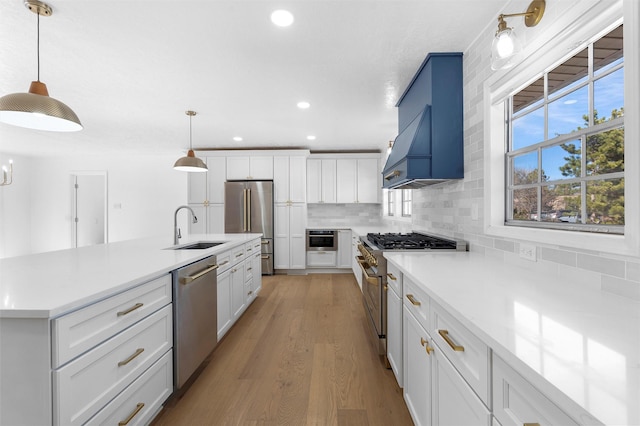 kitchen featuring a sink, decorative backsplash, white cabinetry, high quality appliances, and light wood-type flooring