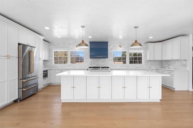 kitchen featuring light countertops, white cabinets, a healthy amount of sunlight, and high end fridge