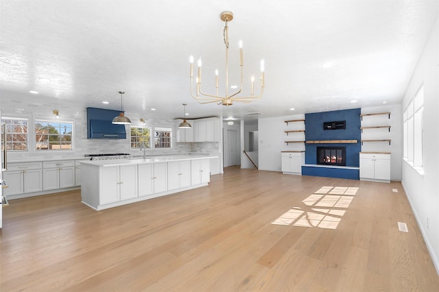 kitchen with light countertops, white cabinets, light wood-style floors, and backsplash