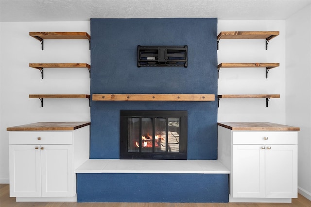 details featuring a textured ceiling and a glass covered fireplace