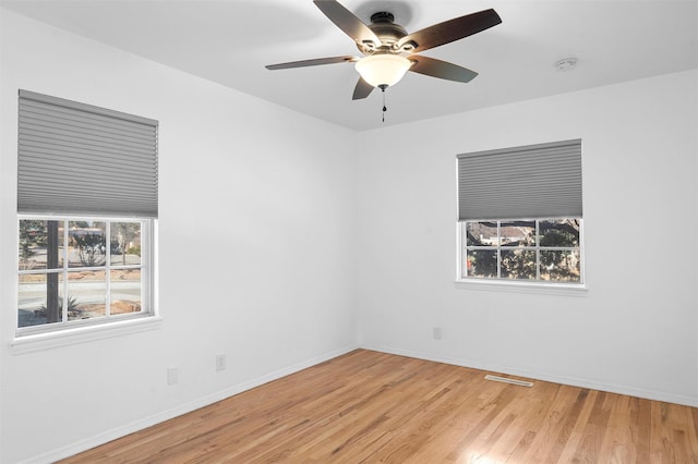 spare room featuring baseboards, plenty of natural light, visible vents, and wood finished floors