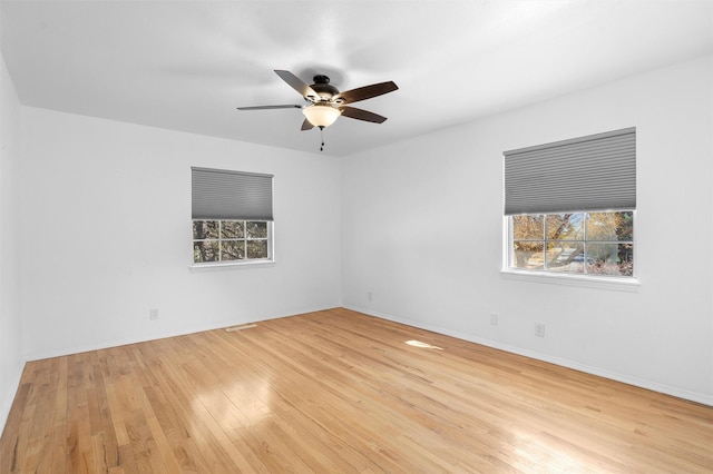 unfurnished room featuring baseboards, plenty of natural light, wood finished floors, and a ceiling fan