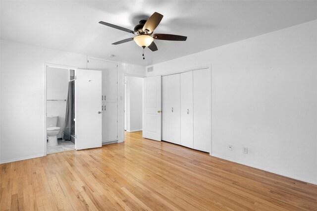 unfurnished bedroom with light wood finished floors, baseboards, a closet, ensuite bath, and a ceiling fan