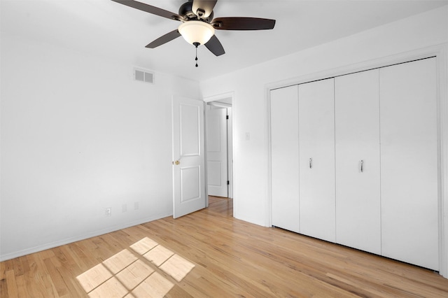 unfurnished bedroom with a closet, a ceiling fan, visible vents, and light wood finished floors