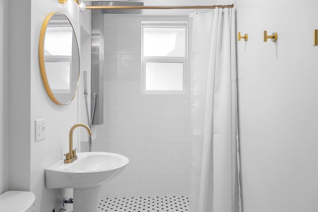 bathroom with a sink, toilet, and a tile shower