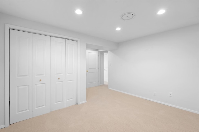 unfurnished bedroom featuring recessed lighting, a closet, baseboards, and light colored carpet