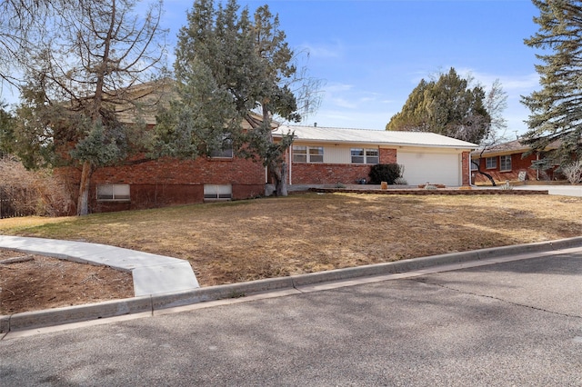 single story home with brick siding, an attached garage, and a front lawn