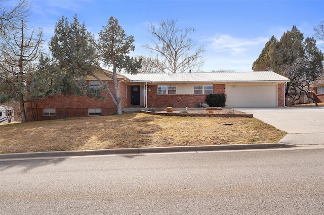 single story home featuring a garage, brick siding, metal roof, and driveway