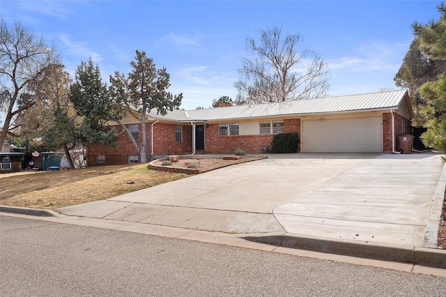 single story home featuring brick siding, a chimney, concrete driveway, and a garage