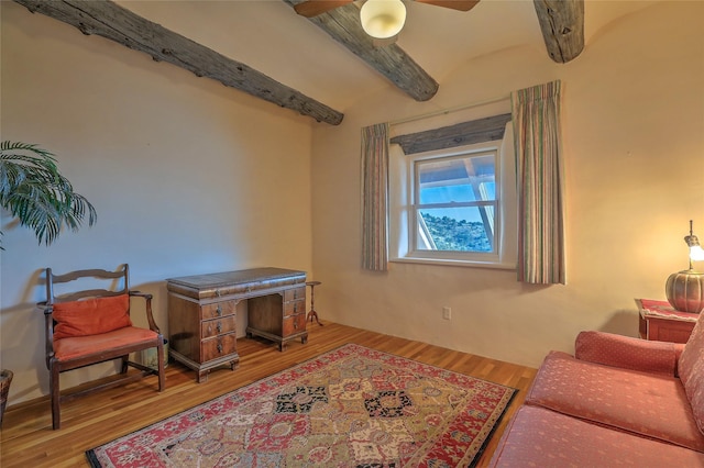 living area featuring beamed ceiling, ceiling fan, and wood finished floors