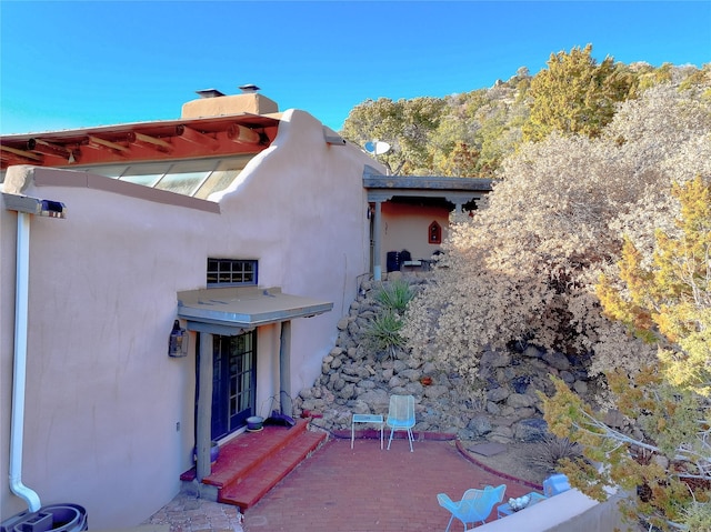 exterior space featuring stucco siding and a chimney