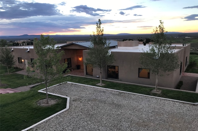 pueblo-style house featuring a patio area, stucco siding, and a yard