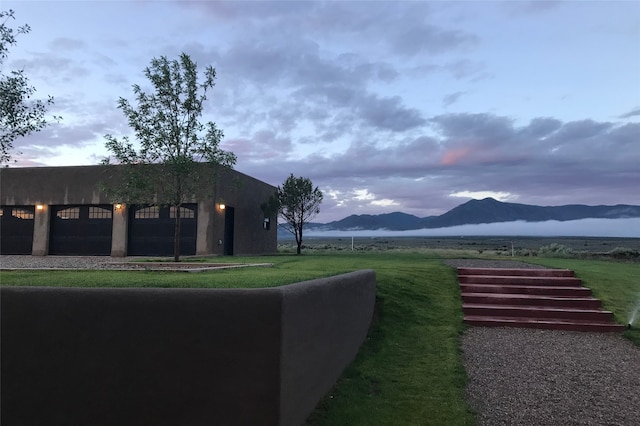 view of yard featuring a mountain view, a garage, driveway, and a rural view