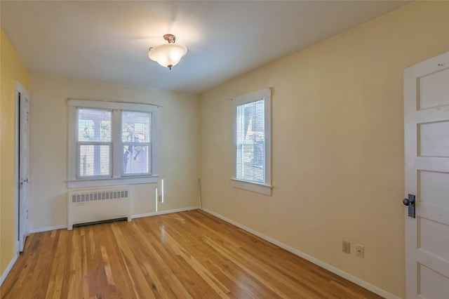 spare room with a wealth of natural light, radiator, baseboards, and wood finished floors