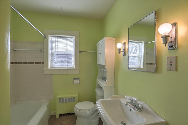 full bath with tile patterned flooring, shower / washtub combination, toilet, radiator heating unit, and a sink