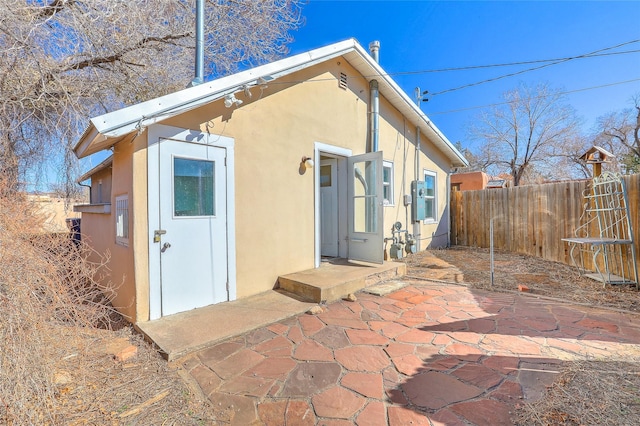 rear view of property with a patio area, stucco siding, and fence