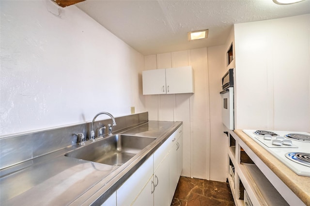 kitchen with stainless steel counters, white cabinets, white appliances, a textured ceiling, and a sink