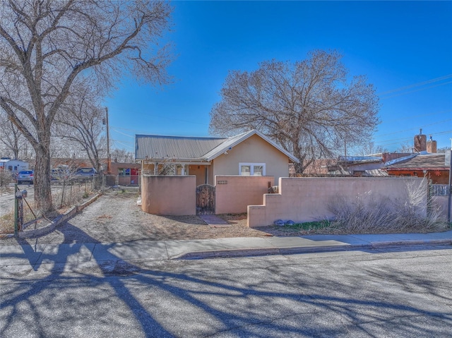 view of side of home featuring a fenced front yard, stucco siding, and metal roof