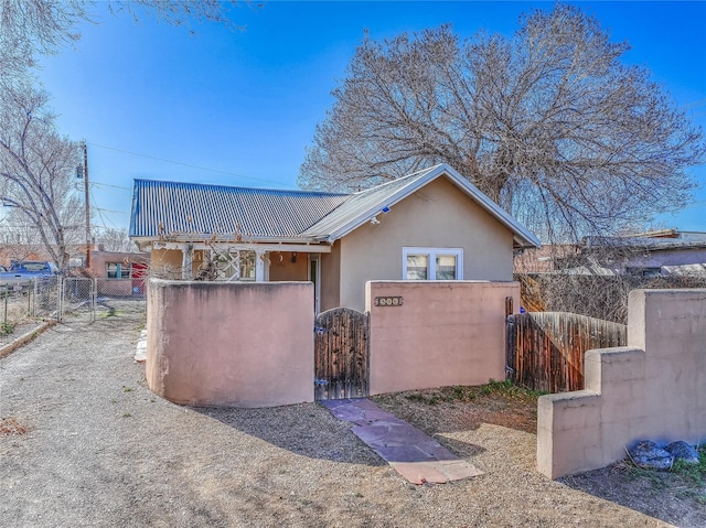 view of home's exterior with metal roof, a fenced front yard, stucco siding, and a gate