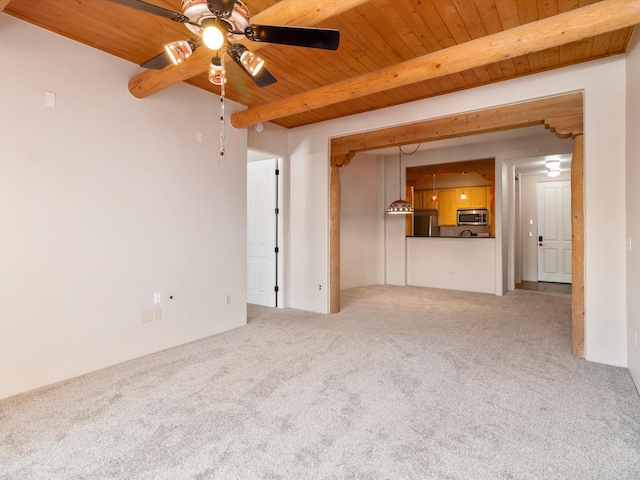 unfurnished living room featuring beam ceiling, carpet floors, wooden ceiling, and a ceiling fan