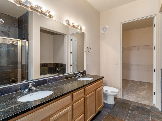 full bath featuring double vanity, a shower stall, a walk in closet, and a sink