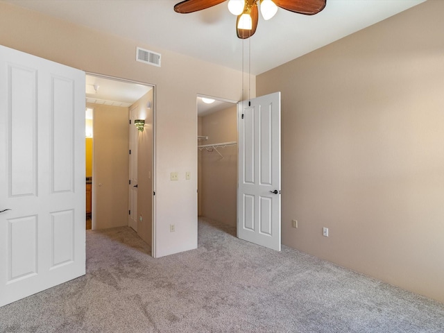 unfurnished bedroom with visible vents, a walk in closet, ceiling fan, carpet, and a closet