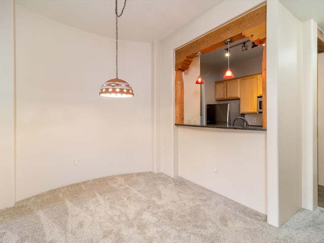 interior space featuring decorative light fixtures, carpet flooring, stainless steel appliances, and dark countertops