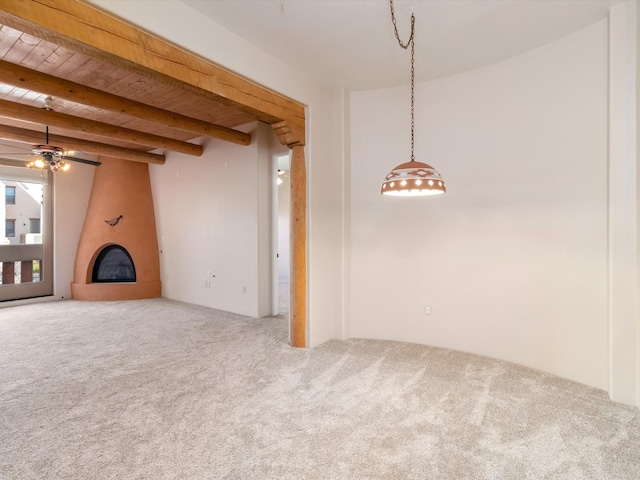 unfurnished living room featuring beamed ceiling, a ceiling fan, a fireplace, and carpet flooring