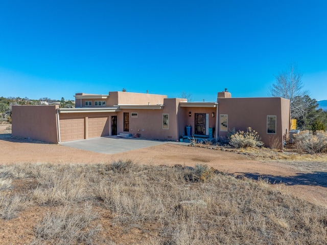 southwest-style home featuring stucco siding, an attached garage, and driveway