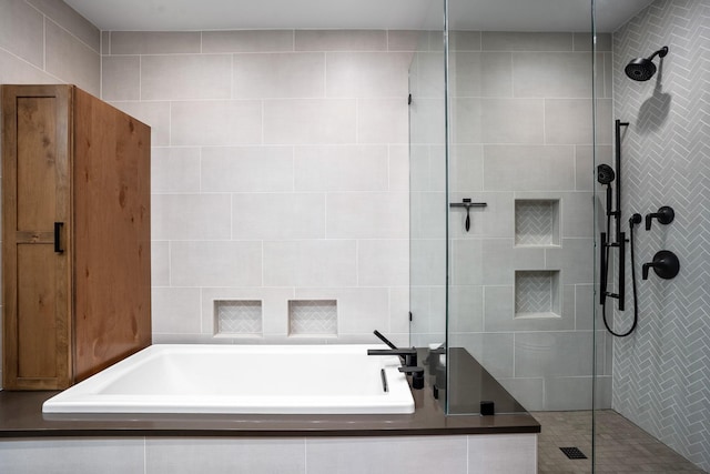 bathroom with a bath, tiled shower, and tile walls