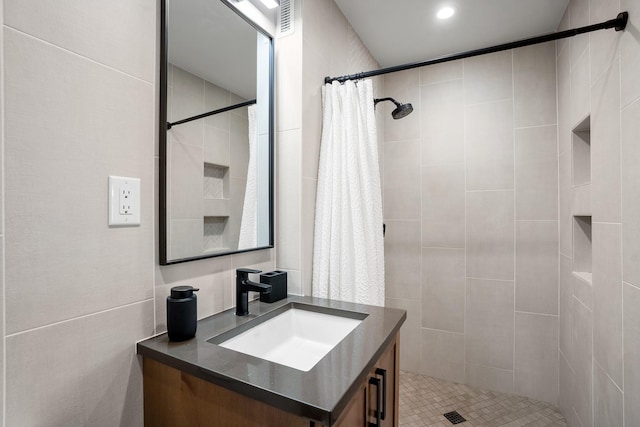 full bathroom featuring tiled shower and vanity