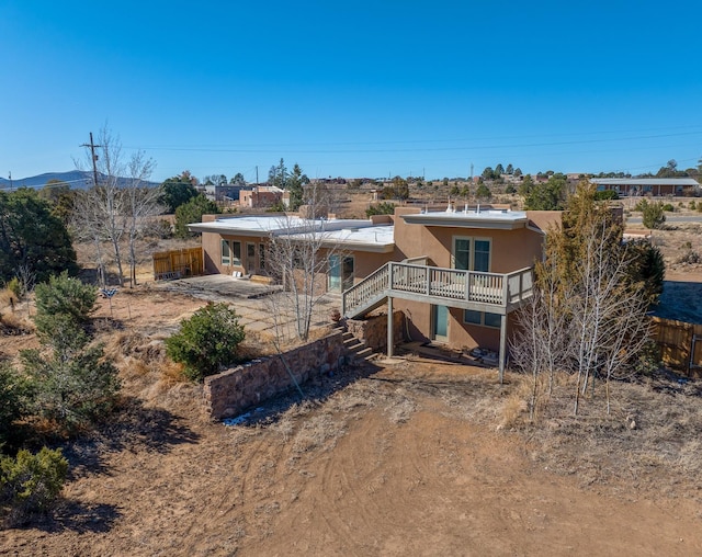 rear view of property with a deck, stairway, fence, and stucco siding