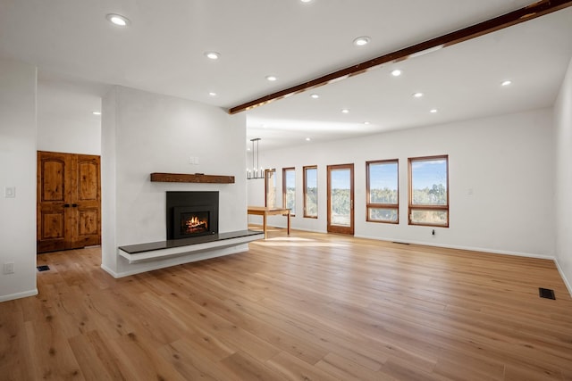 unfurnished living room with light wood-style flooring, recessed lighting, visible vents, and a warm lit fireplace