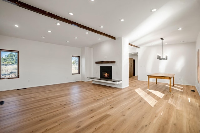 unfurnished living room with light wood finished floors, visible vents, baseboards, a lit fireplace, and recessed lighting