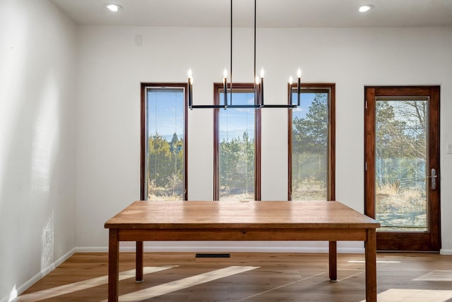 unfurnished dining area featuring wood finished floors, a notable chandelier, recessed lighting, and baseboards