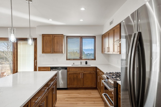 kitchen with a sink, light countertops, brown cabinetry, and stainless steel appliances