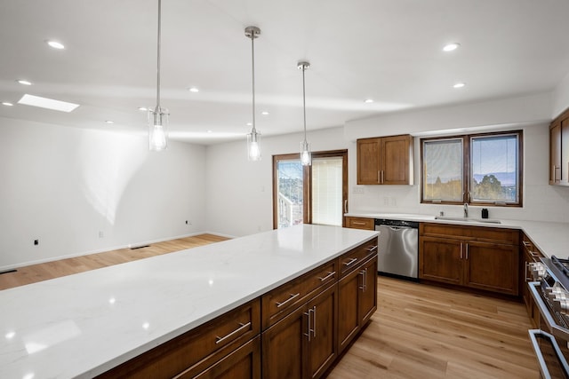 kitchen featuring light wood-style flooring, a sink, decorative light fixtures, recessed lighting, and appliances with stainless steel finishes