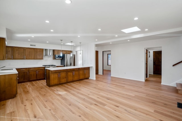 kitchen with a sink, appliances with stainless steel finishes, wall chimney exhaust hood, and light countertops