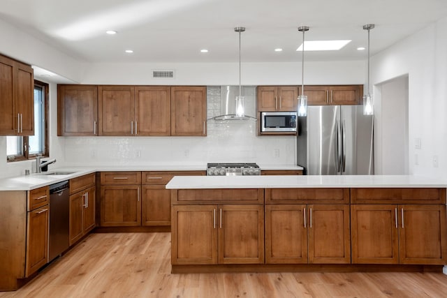 kitchen with visible vents, brown cabinets, appliances with stainless steel finishes, wall chimney exhaust hood, and a sink