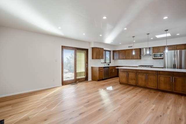 kitchen with baseboards, light wood-style flooring, light countertops, appliances with stainless steel finishes, and wall chimney range hood