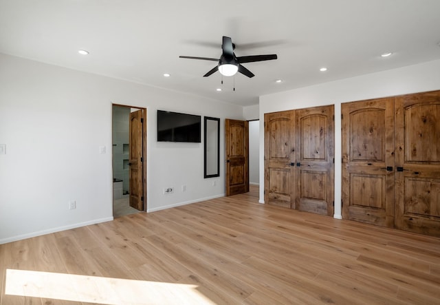 unfurnished bedroom featuring baseboards, light wood-style flooring, recessed lighting, multiple closets, and ensuite bathroom