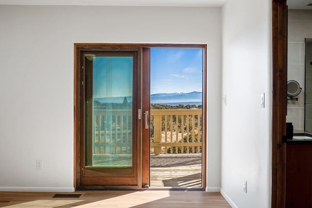 doorway featuring a mountain view, wood finished floors, visible vents, and baseboards