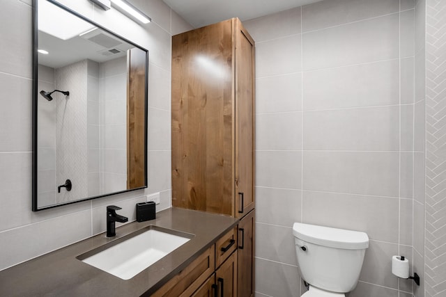 bathroom with toilet, tile walls, and vanity