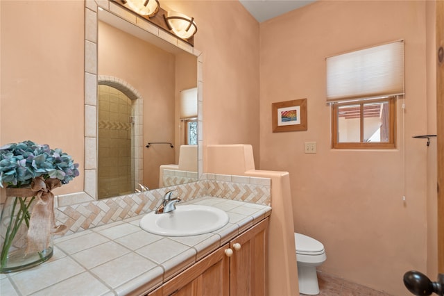 full bathroom featuring tiled shower, a healthy amount of sunlight, toilet, and vanity