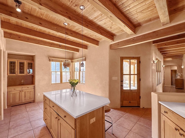 kitchen with beamed ceiling, a kitchen bar, a kitchen island, light tile patterned flooring, and wood ceiling