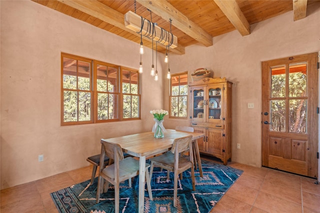 dining area with beam ceiling, tile patterned floors, and wood ceiling