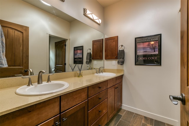 bathroom featuring double vanity, wood tiled floor, baseboards, and a sink