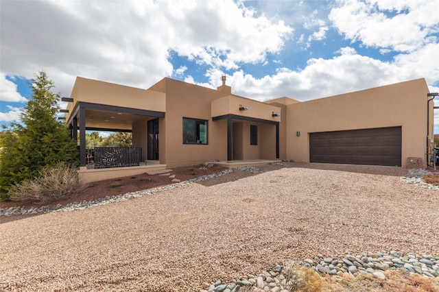 southwest-style home featuring stucco siding, gravel driveway, and a garage